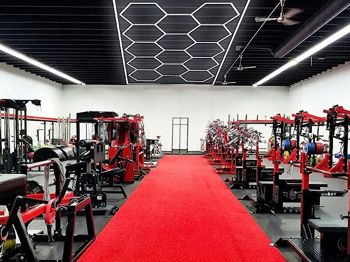 A gym with a red carpet, Hex Lights, and equipment.