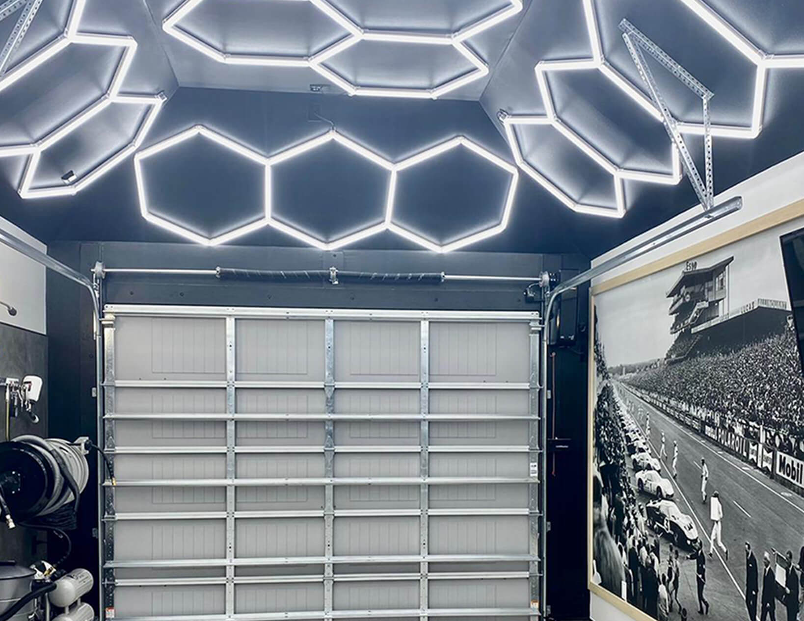 A garage featuring custom hex lighting with a photo of a race car on the ceiling.