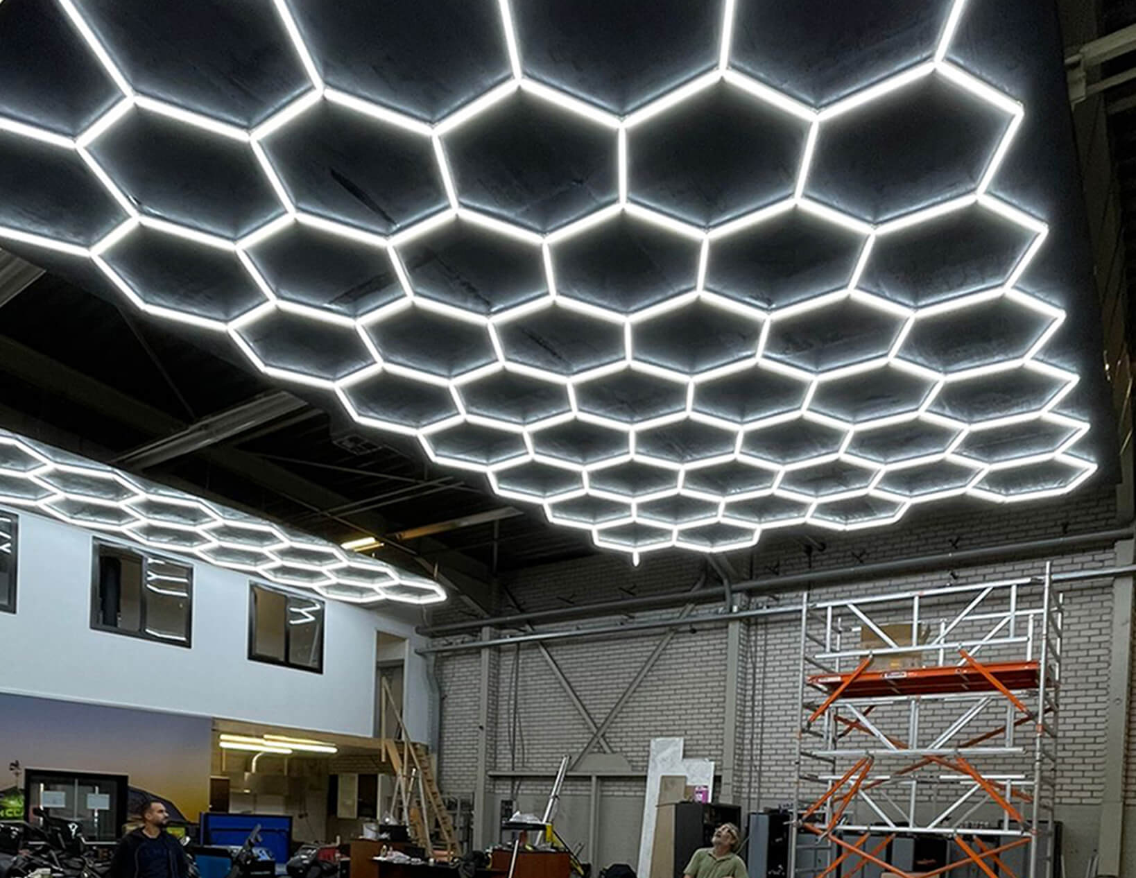 The ceiling of a large building is lit up with custom hex lighting.