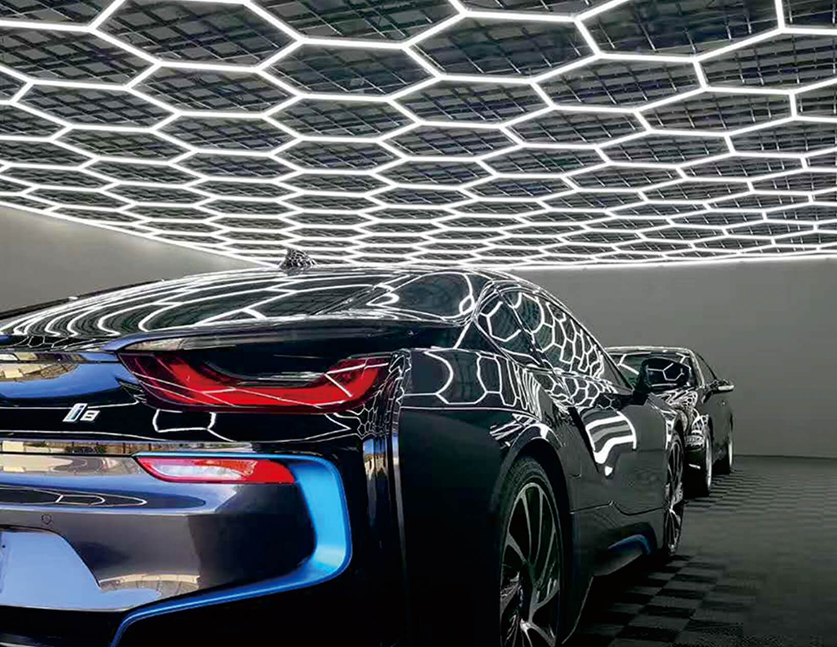 The BMW i8, illuminated by custom hex lighting, is parked in a showroom.