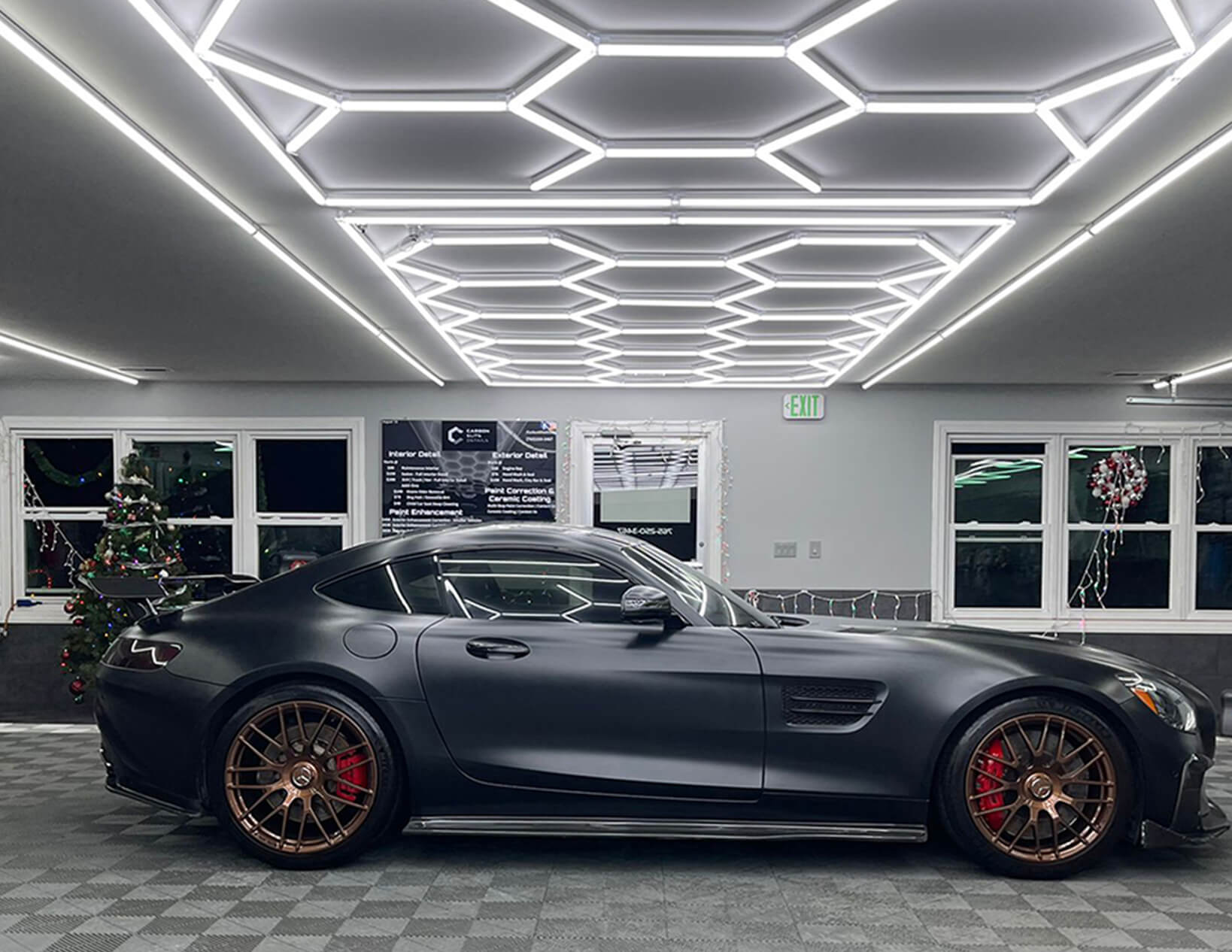 A black Mercedes AMG GT is parked in a garage, illuminated by Canada Hex Lights.