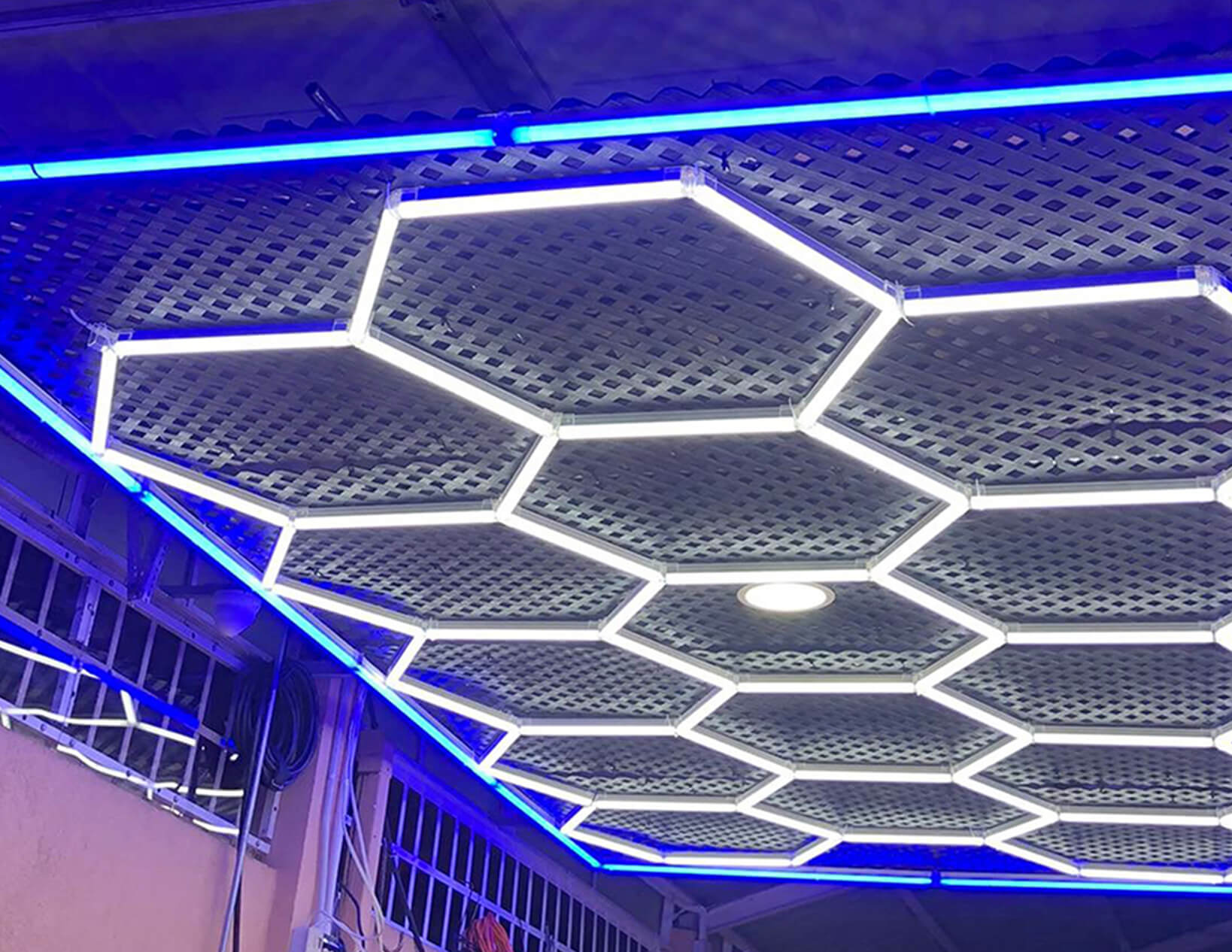 A ceiling with blue LED lights and a hexagonal pattern featuring custom Hex Lighting.