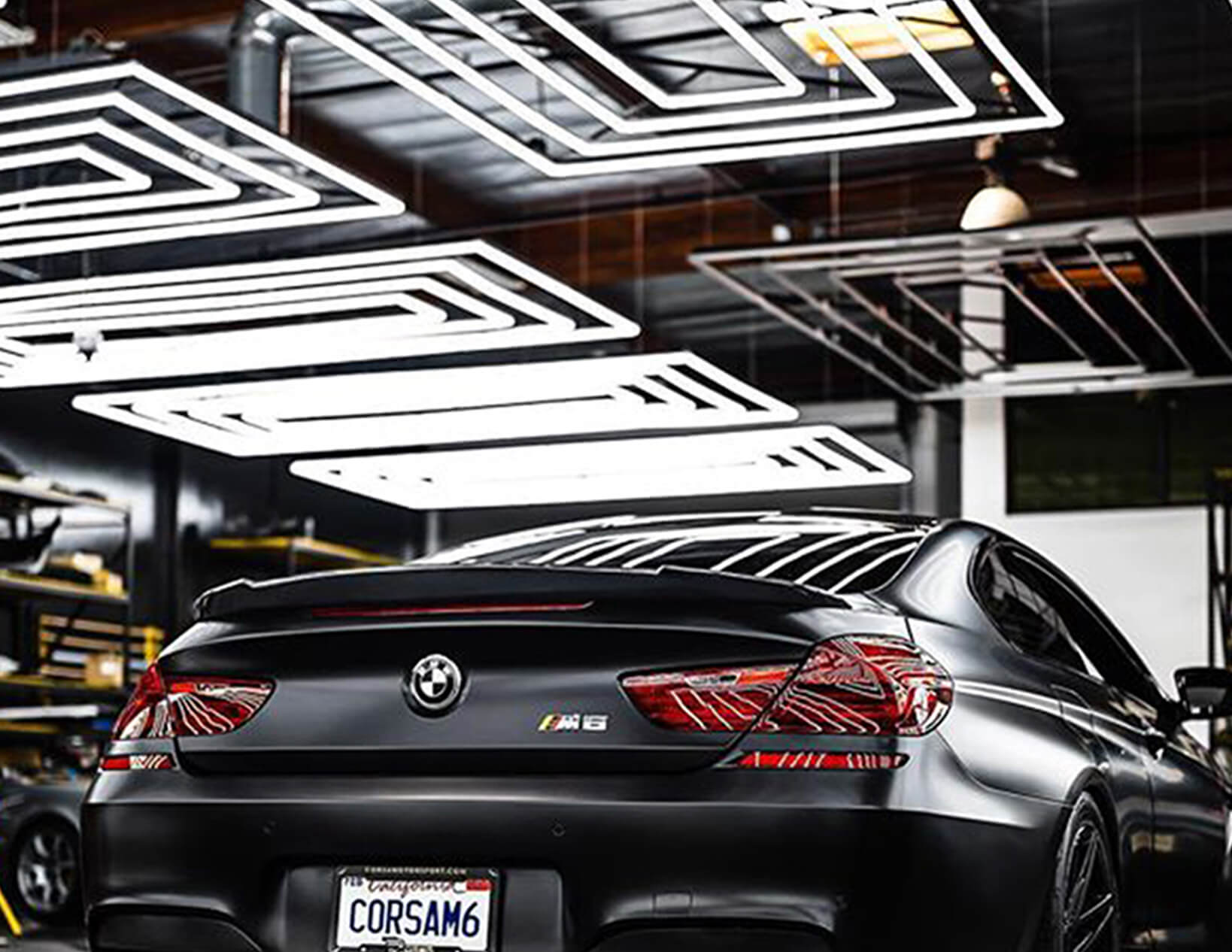 A black BMW M6, illuminated by Canada Hex Lights, is parked in a garage.